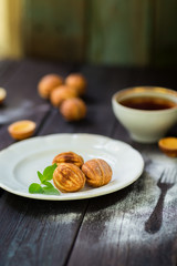 Walnut cookies on a white plate, wooden background