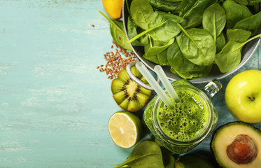 Healthy green smoothie and ingredients on blue background