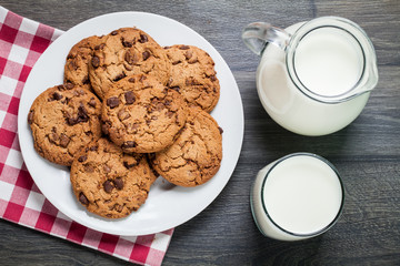 Chocolate chip cookies, milk, rustic wood background, top view