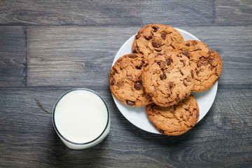 Chocolate chip cookies, milk, rustic wood background, top view