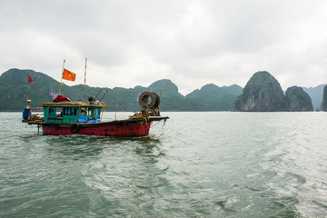 Old fishing boat with Vietnam flag sailing in the calm waters around Cat Ba Island, Vietnam