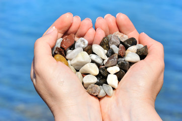 Closeup of woman hands holding sea pebbles form heart shape