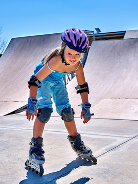 Child riding on roller skates in skatepark. Child in protection for skates