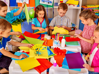 Group kids holding colored paper on table in kindergarten . Children writting letter Santa Claus.