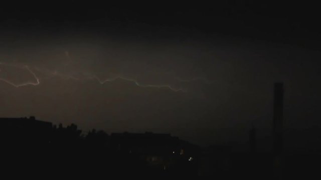 Slow motion video clip of lightning and severe thunderstorm clouds above the city at night.