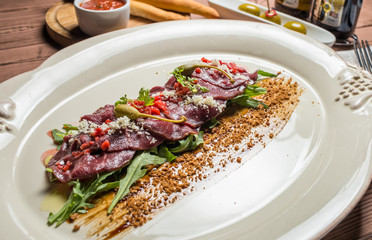 carpaccio with deer served on white plate