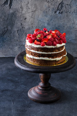 Naked cake with raspberries, strawberries and blueberries on stone table. Natural life