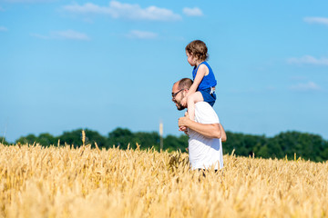 father and son having fun outdoor in wheat field