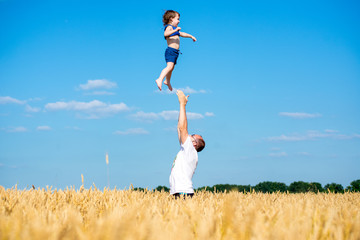 father tosses child in a wheat field