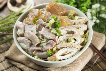 Chinese bowl of vermicelli noodle with pig's guts and herbs on the table