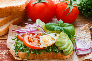 Healthy Breakfast - toast with egg, tomato, red onion, avocado and greens
