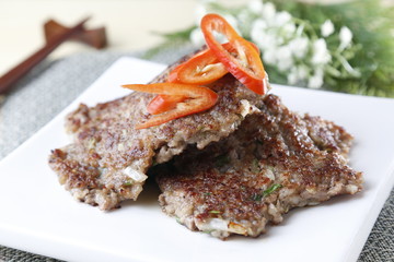 Grilled meat on white plate with sliced chili