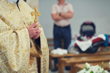 Beautiful golden cross in male hands of priest wearing gold robe