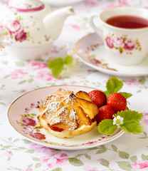 Cream puffs or profiterole filled with whipped cream, powdered sugar topping served with strawberries on the table
