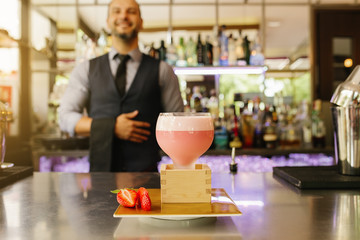 Barman is making cocktail at night club.