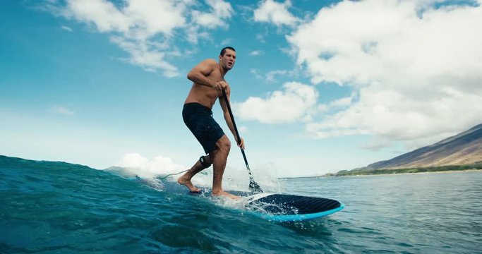 Surfer riding blue ocean wave stand up paddle boarding