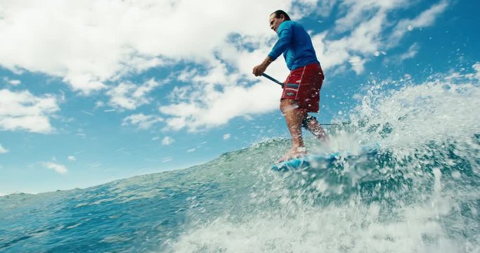 Surfer riding blue ocean wave stand up paddle boarding