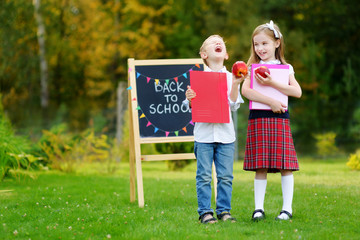 Two adorable little schoolkids feeling excited about going back to school