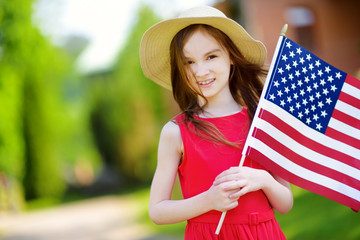 Adorable little girl holding american flag outdoors on beautiful summer day
