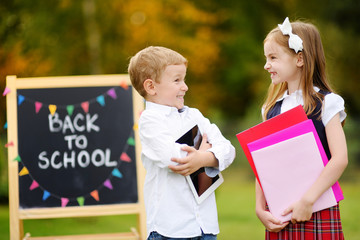Two adorable little schoolkids feeling excited about going back to school