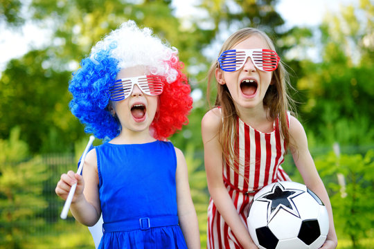 Two funny little sisters supporting and cheering their national football team
