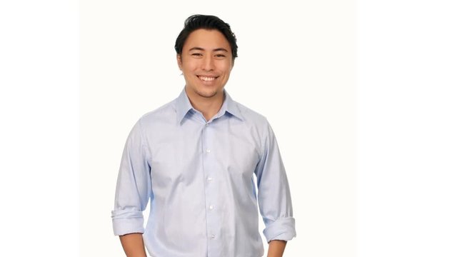 Trendy Attractive Man Wearing A Light Blue Shirt, Smiling And Walking Towards Camera In Front Of A White Background. 