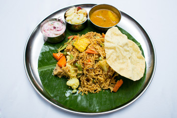 Indian vegetarian food with fried rice on banana leaf tray