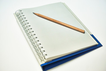 Wooden pencil put on a notebook. Selective focus on pencil which is put on the notebook.