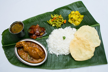 Indian meal with braised chiken and plain rice on banana leaf tray