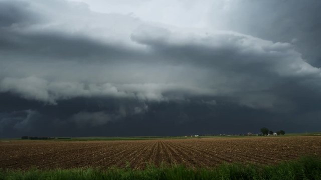 Huge shelf cloud out ahead of a cool outflow of air from a thunderstorm over farmland, time lapse