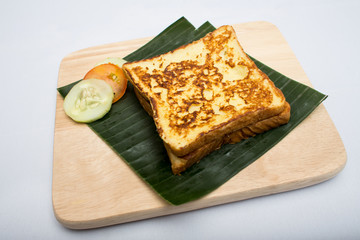 Indian tray meal with roasted sandwich and cucumber, tomato on banana leaf