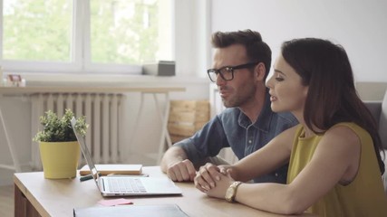 Happy couple at home together browsing internet on laptop - Powered by Adobe