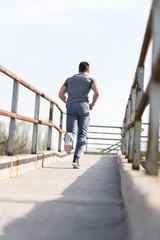 Fototapeta na wymiar Full length portrait of handsome runner jogging fast down the br