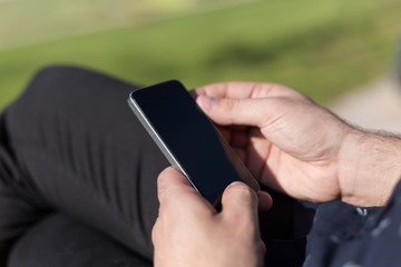 Closeup of smiling handsome bearded man in  shirt using mobile p