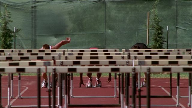 Slow-motion hurdlers racing toward camera