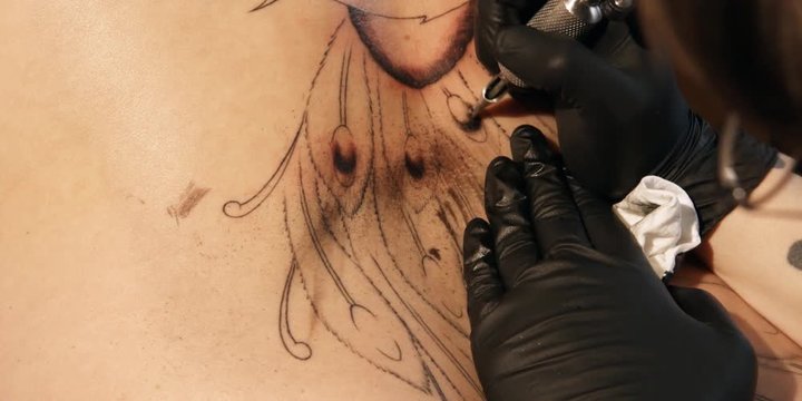 A tattoo being drawn on a woman's shoulder