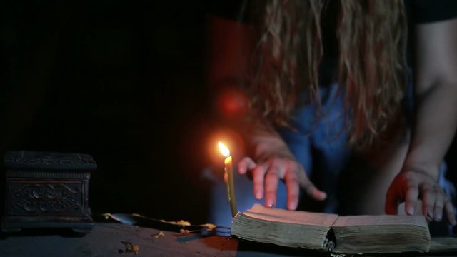 witch holding the magic ritual. old book and candle. halloween