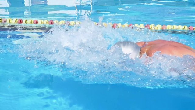 Professional swimmer is swimming breaststroke in a pool using paddles. Breaststroke training.