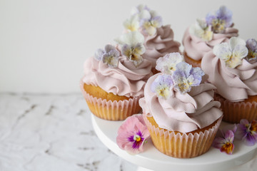 Fototapeta na wymiar Purple cupcakes with sugared edible flowers on cake stand copy s