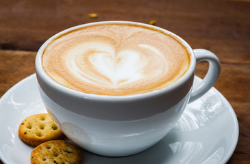 cup of cappucino and biscuits on a wood background