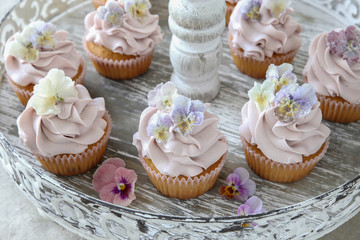 Purple cupcakes with sugared edible flowers on vintage cake stand
