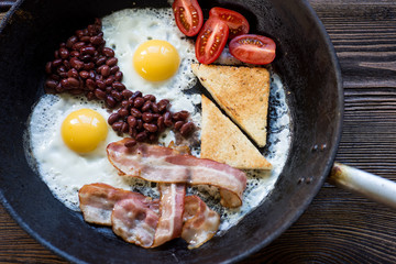 Full English cooked breakfast with bacon,  fried egg and toasts.