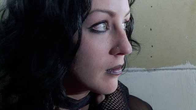 Three-quarter profile close-up of young woman with black lipstick and nose stud