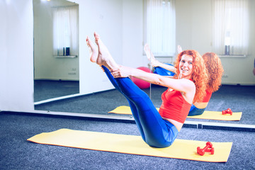 Fototapeta na wymiar young female instructor doing pilates exercises in sport club