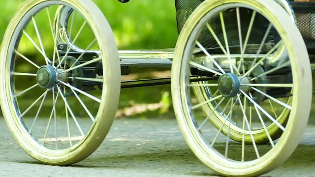 Slow motion. Wheels of old baby carriage and leg