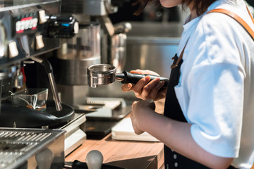 Human hand holding a portafilter with morning coffee

