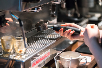 Human hand holding a portafilter with morning coffee
