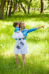 young mother and daughter on a summer walk in the woods in identical dresses