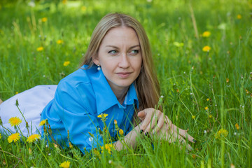 girl lying on the ground among dandelions and grasses