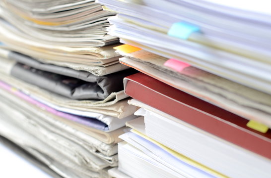 Stack of newspaper and documents with high key tone and blur focus,close-up of newspaper and documents on desk at business office.